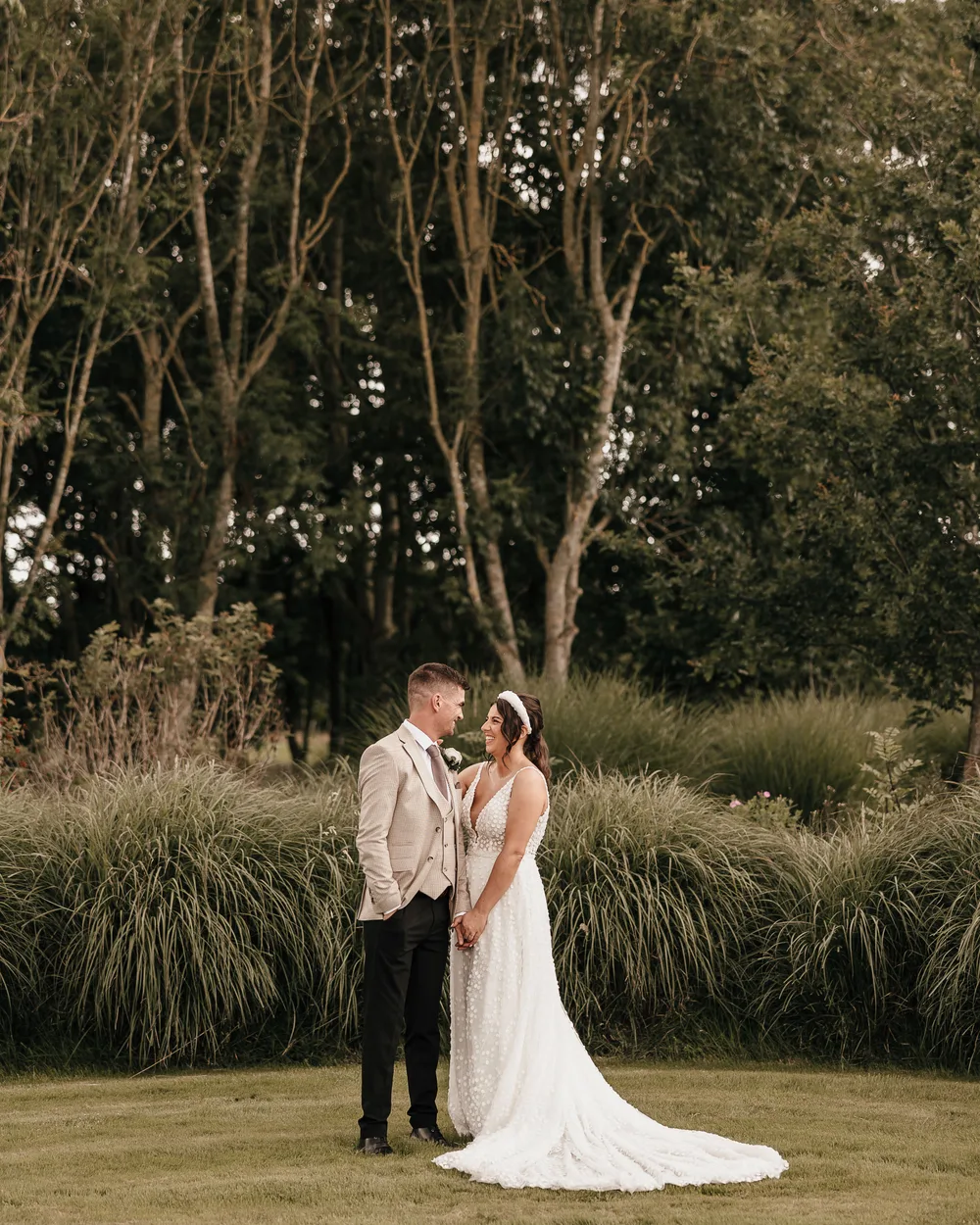 A couple among the tall grasses at the edge of the woodland.