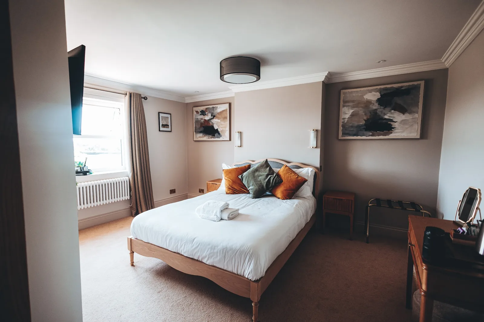 A Farmhouse bedroom with a king bed, a desk and a window over the grounds.