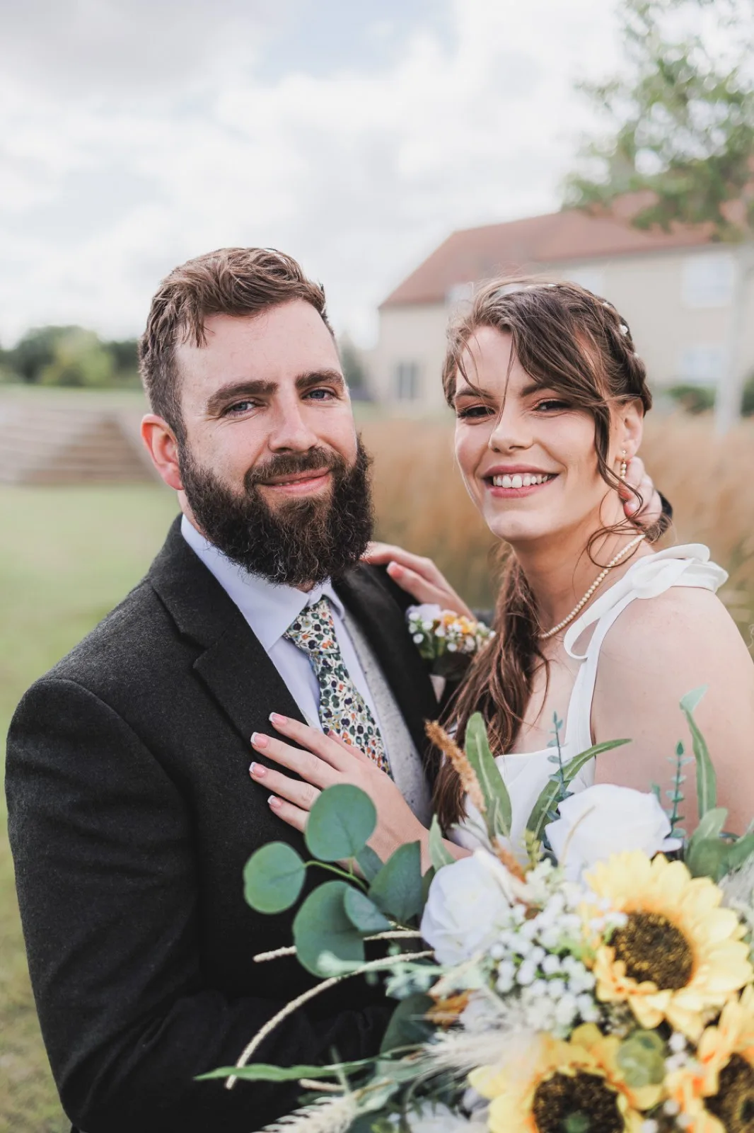 A couple in the grounds with a sunflower bouquet