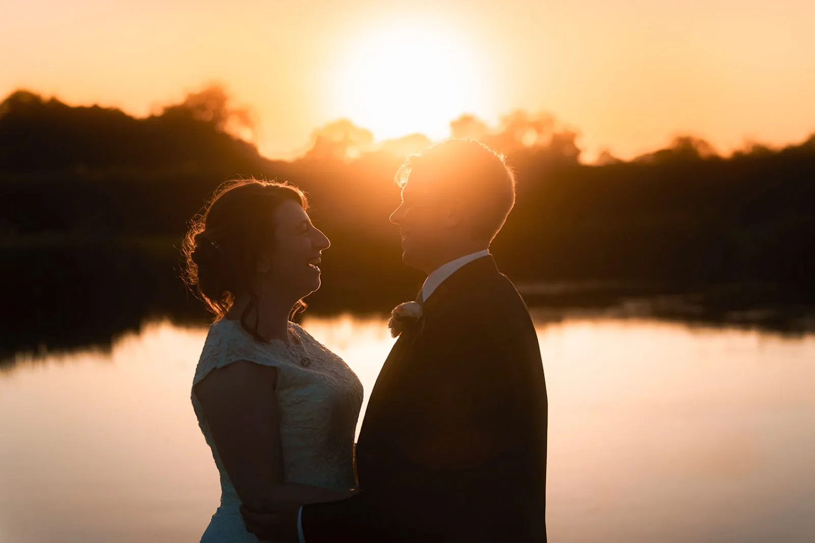 A couple silhouetted at sunset over the lake