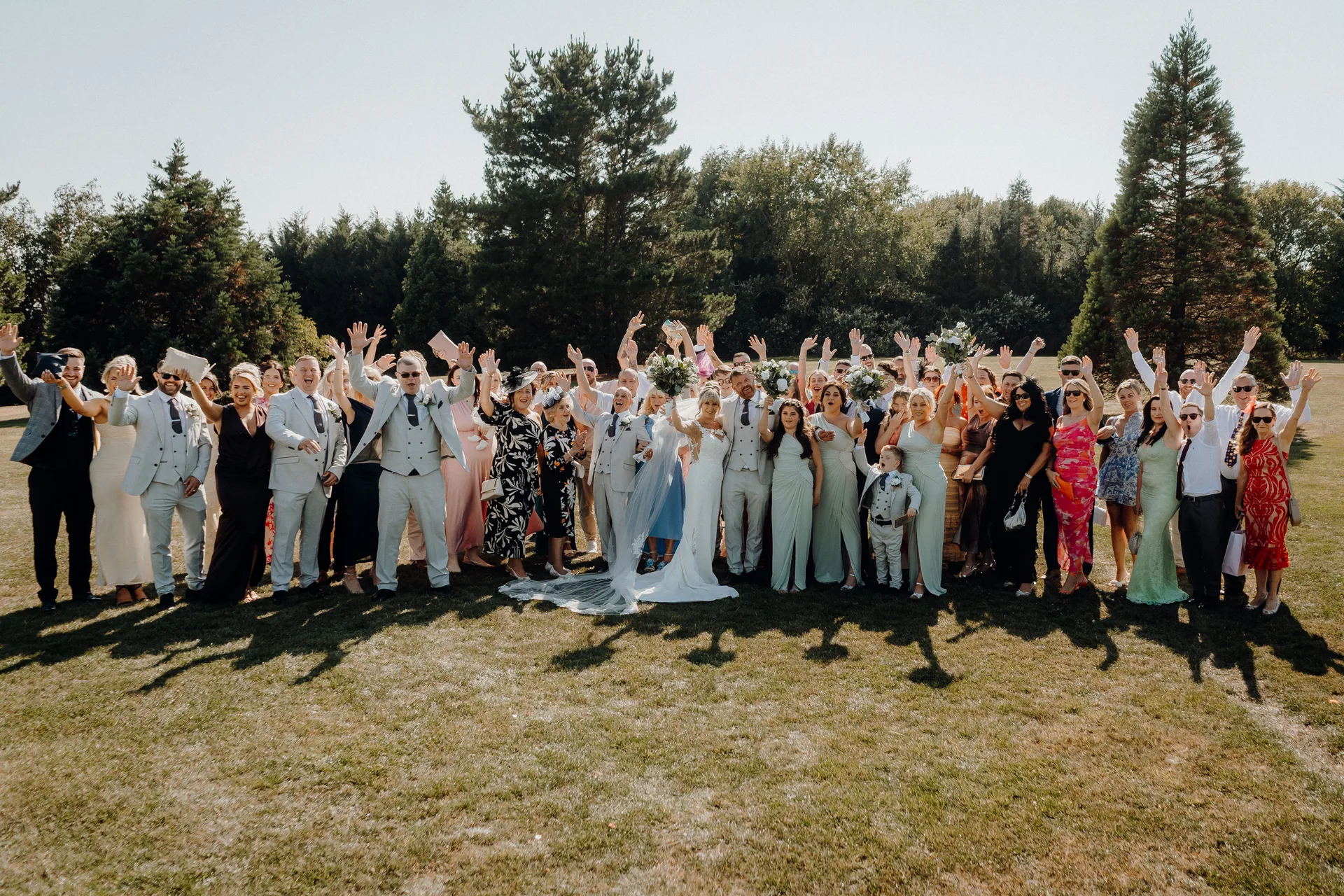 A couple with all their guests cheering on the lawn